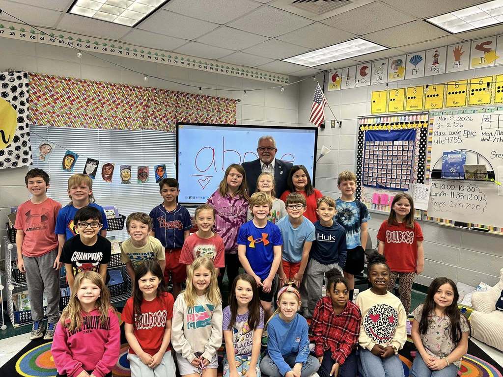 Gardendale Mayor Stan Hogeland poses for a photo with a group of students inside a classroom.