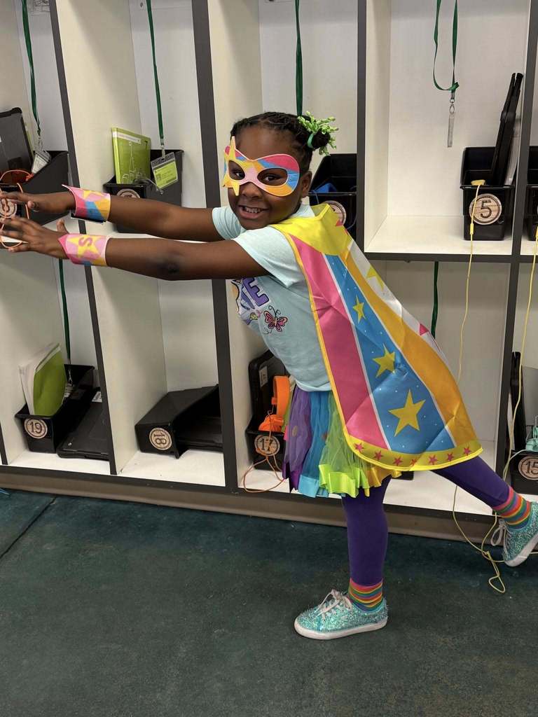 A girl poses like a superhero while wearing a colorful mask and cape.