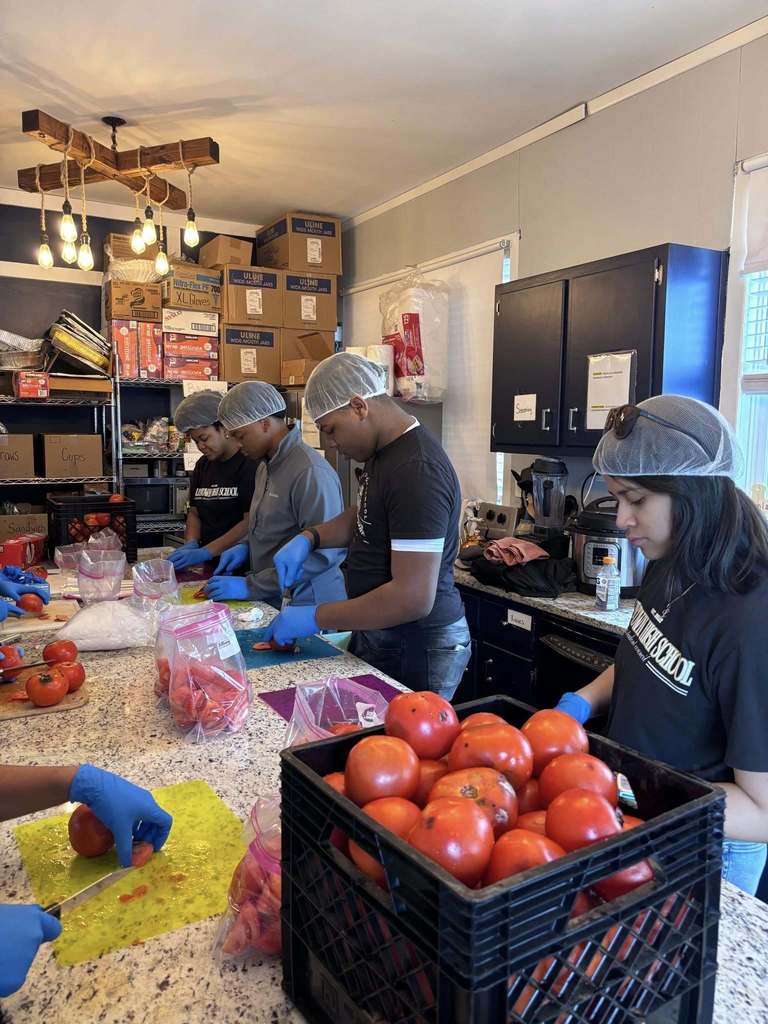 Students cut tomatoes and put them into bags while volunteering at Grace Klein Community.