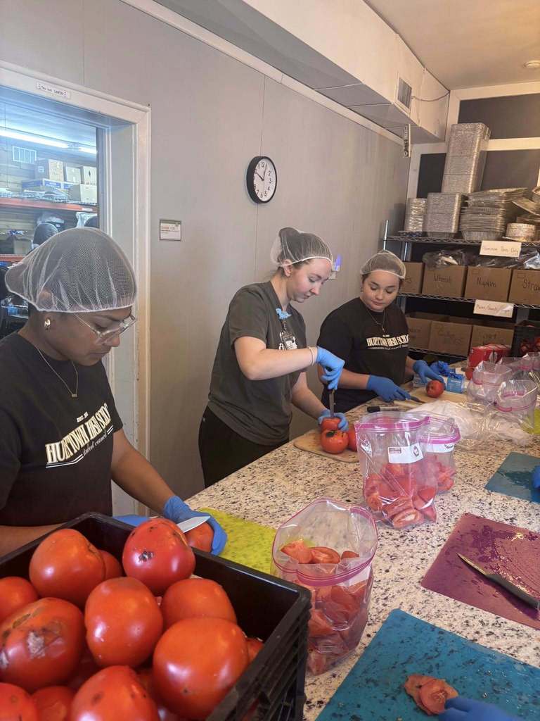Students cut tomatoes while volunteering with Grace Klein Community.