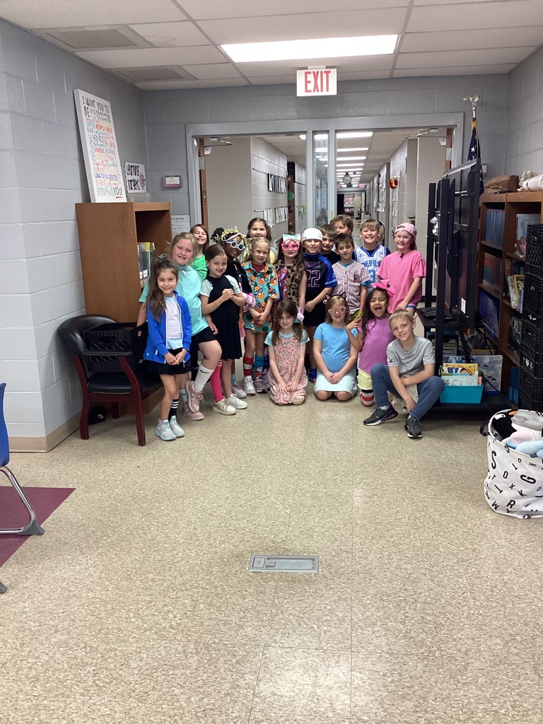 Students posing in front of the library doors in wacky clothes for day 3 of Read Across America week. Students clothing is mismatched and inside out.