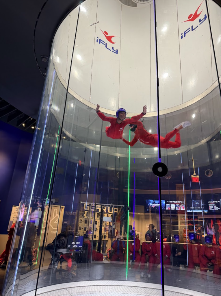 An instructor holds a participant during an indoor skydiving lesson.