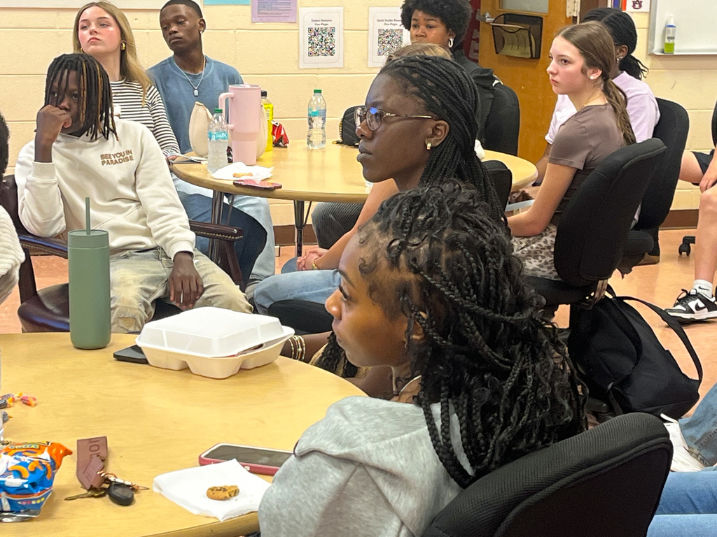 Students sit at a table in a room and look forward while listening to someone talk during the JEFCOED Superintendent's Student Advisory Council meeting. 