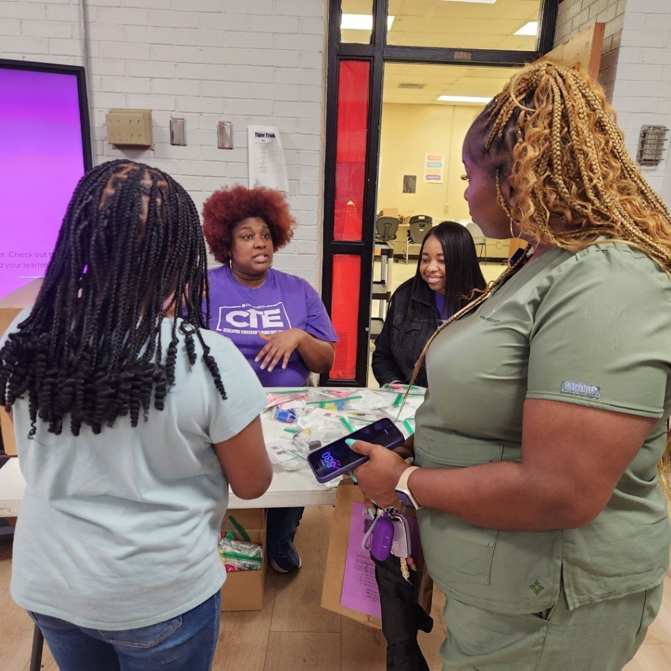 Ms. Sudbury and Ms. Lee discussing with a family about Careera and Technical classes bridging together core subjects. They also explained how their take-home hands-on activities hone in on math and science.