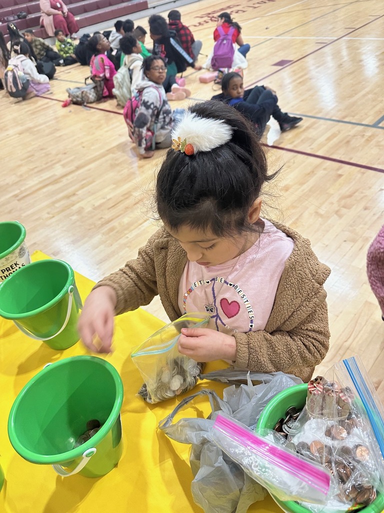 a teacher and students putting coins into a green bucket that will go towards raising fund for peer helpers