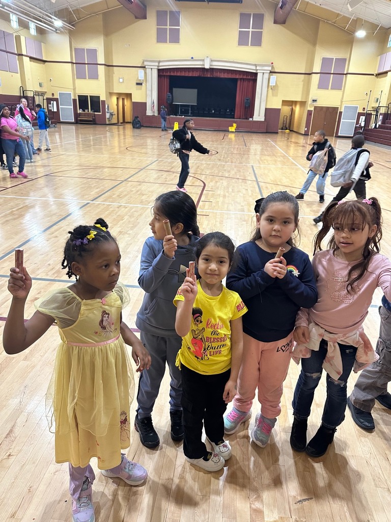 a teacher and students putting coins into a green bucket that will go towards raising fund for peer helpers