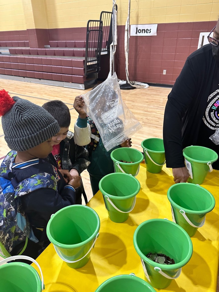 a teacher and students putting coins into a green bucket that will go towards raising fund for peer helpers