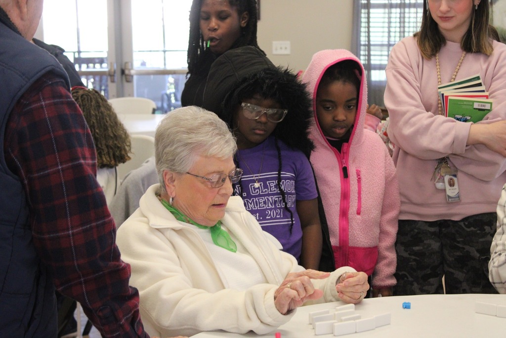 A woman teaches little girls how to play a game.