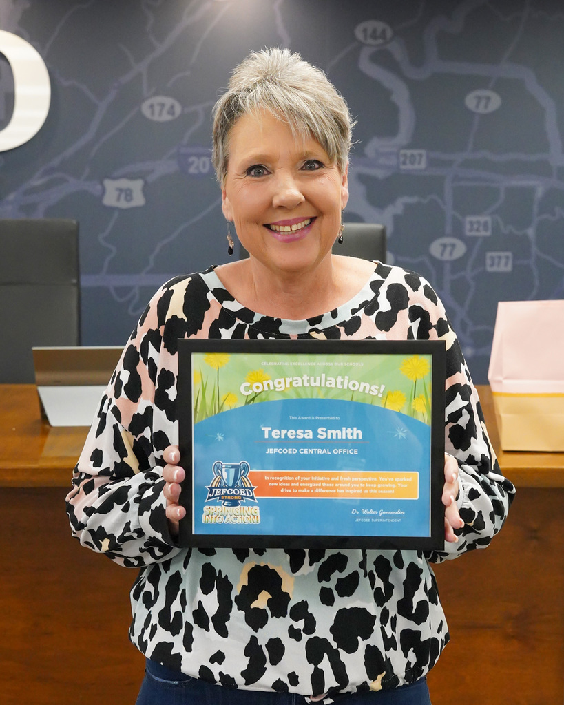 Teresa Smith holds up her award for the JEFCOED Strong Award. She is smiling at the camera. 