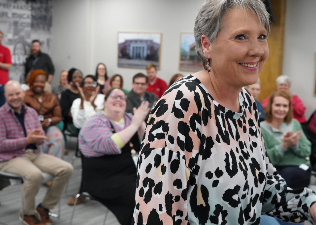 A close up image of a woman walking up to receive an award. The crowd is clapping in the background. 
