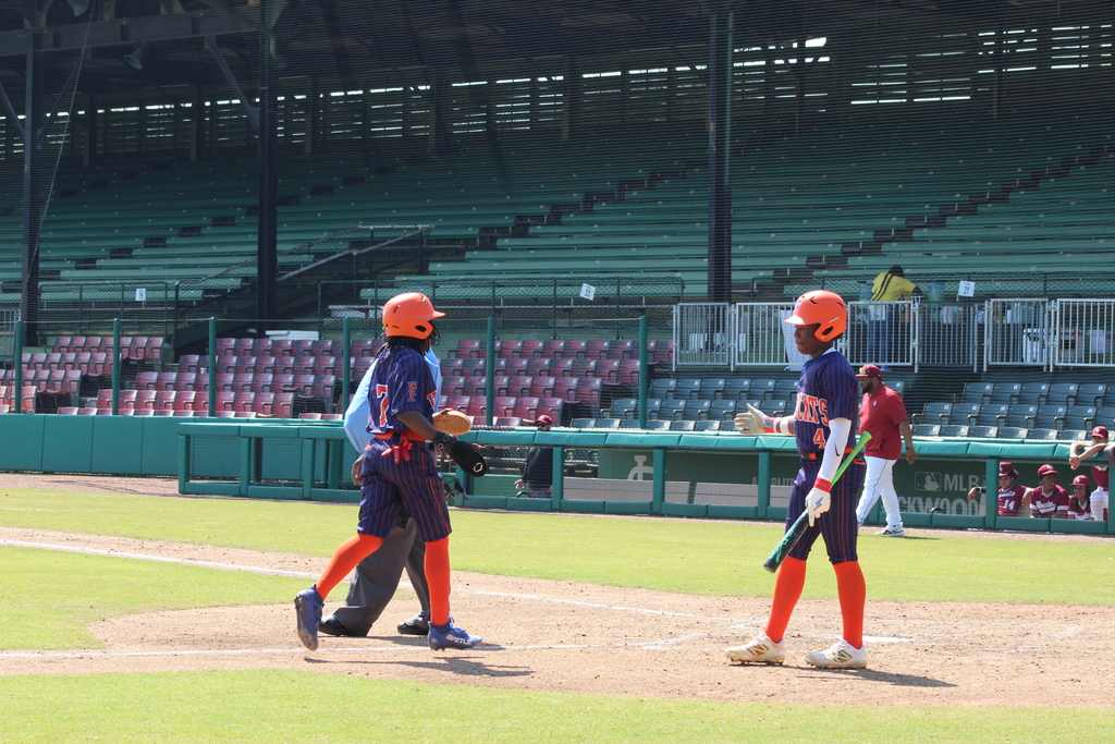 Two Fultondale High School baseball players walk towards each other with a hand out, preparing to high five. 