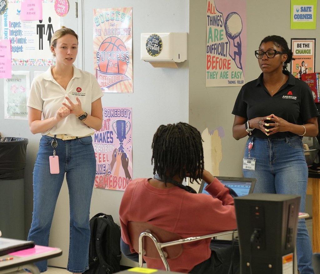 Two women wearing ACIPCO shirts speak to a classroom of studnets.