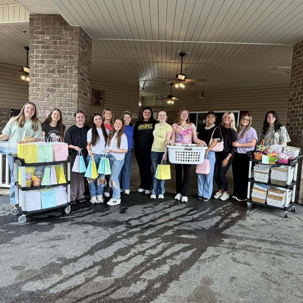 Corner High School students stand for a photo and smile outside a nursing home. The students hold care packages they put together for the residents. 