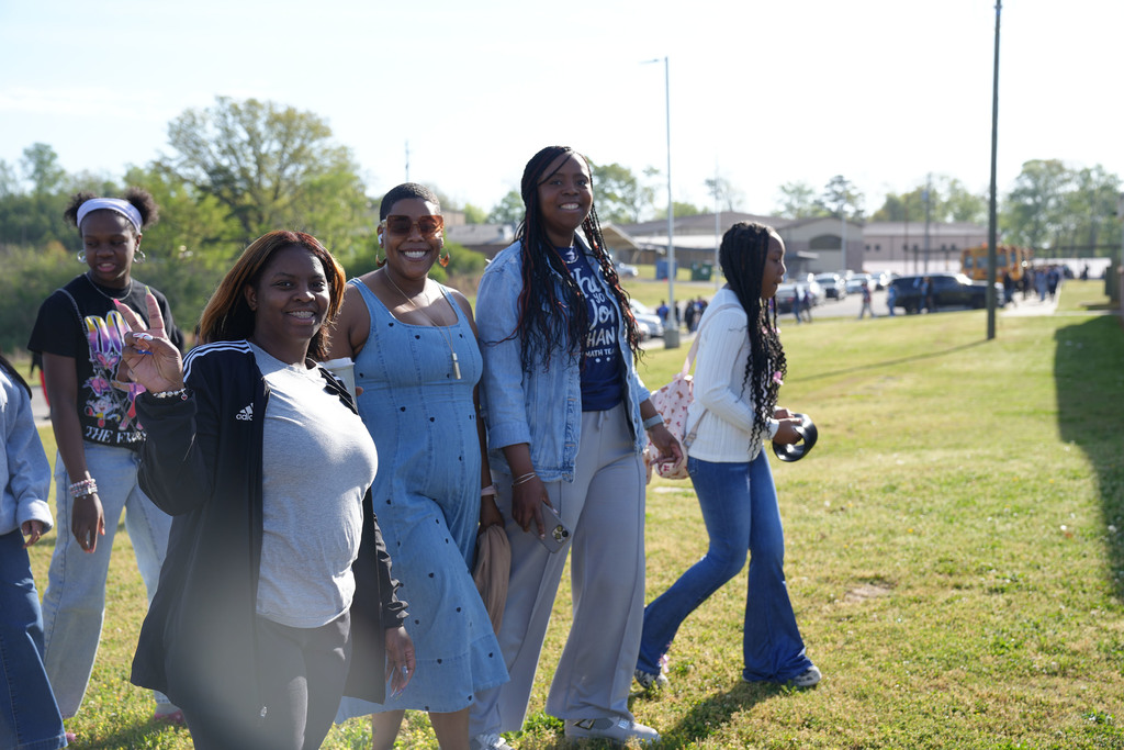A group of teachers smile for a photo while participating in an Autism Awareness Day walk outside Erwin Middle School.