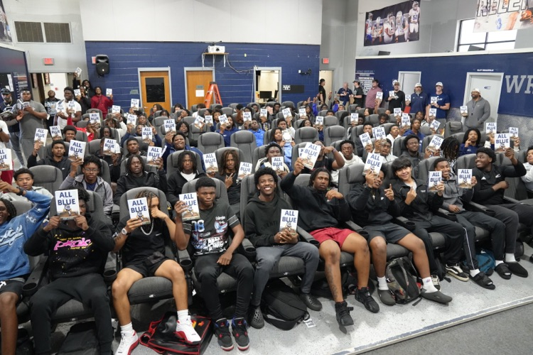 CCHS football players hold up copies of “All Blue: A Season of Leadership, Legacy, and Lessons Learned"