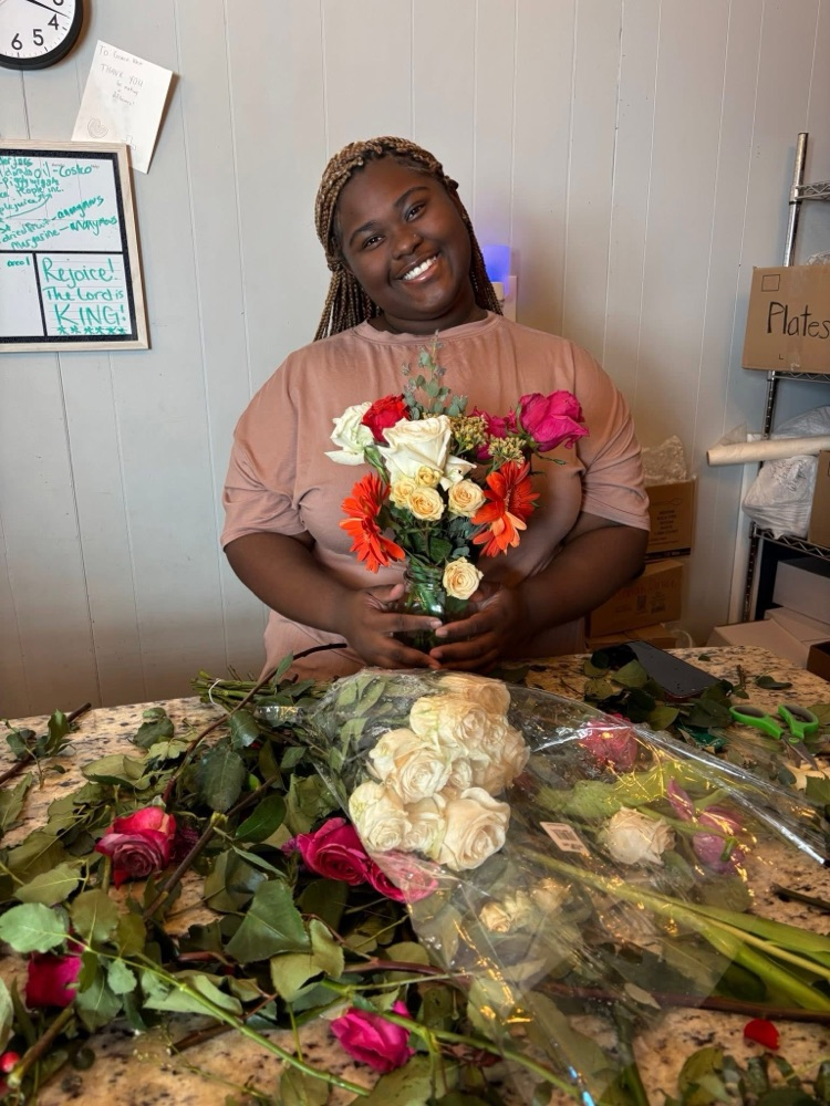 A student smiles while holding a bouquet of flowers she made  
