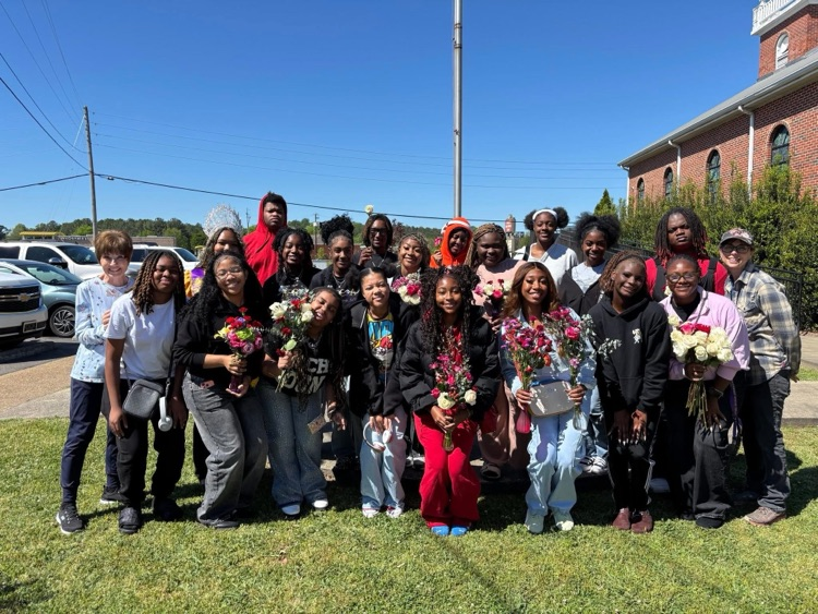 A group of students stand together for a photo outside a building  