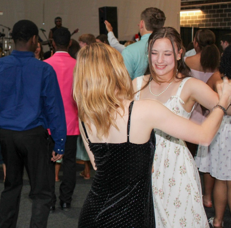 Two girls wearing formal dresses smile and dance at JEFCOED’s Exceptional Prom.
