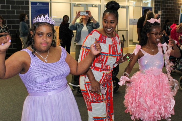 Students wearing formal dresses dance with a woman at JEFCOED’s Exceptional Prom  