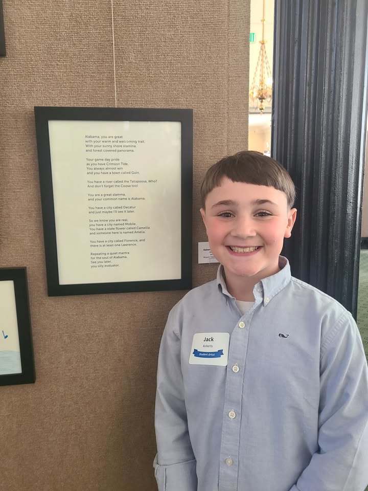 Mount Olive student Jack Roberts smiles for a photo in front of his winning poem at the Alabama State Capitol. His poem won at the Father Goose Writing Festival.