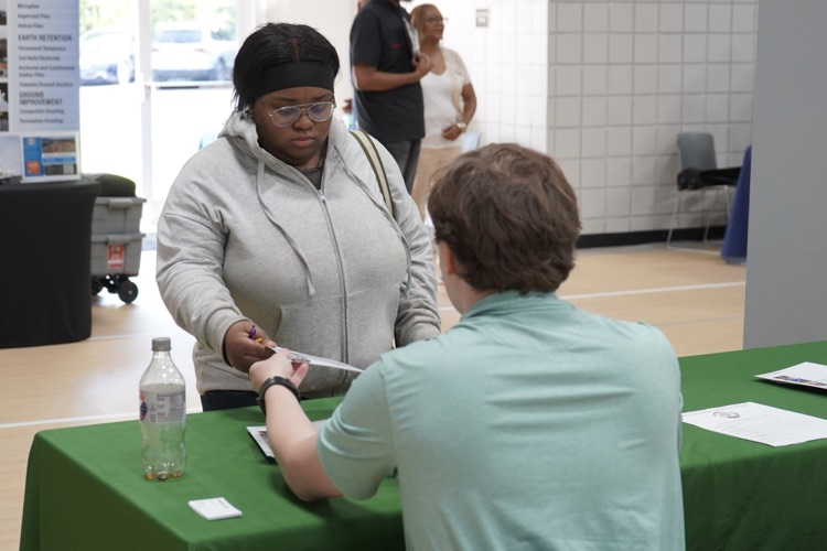 A man hands a piece of paper to a student during the Jefcoed Career Connection Day at the Gardendale Civic Center.