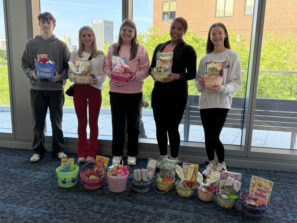 Members of Gardendale High School's Interact Club stand together for a photo inside Children's of Alabama and smile. The members hold baskets with toys and activities inside them.