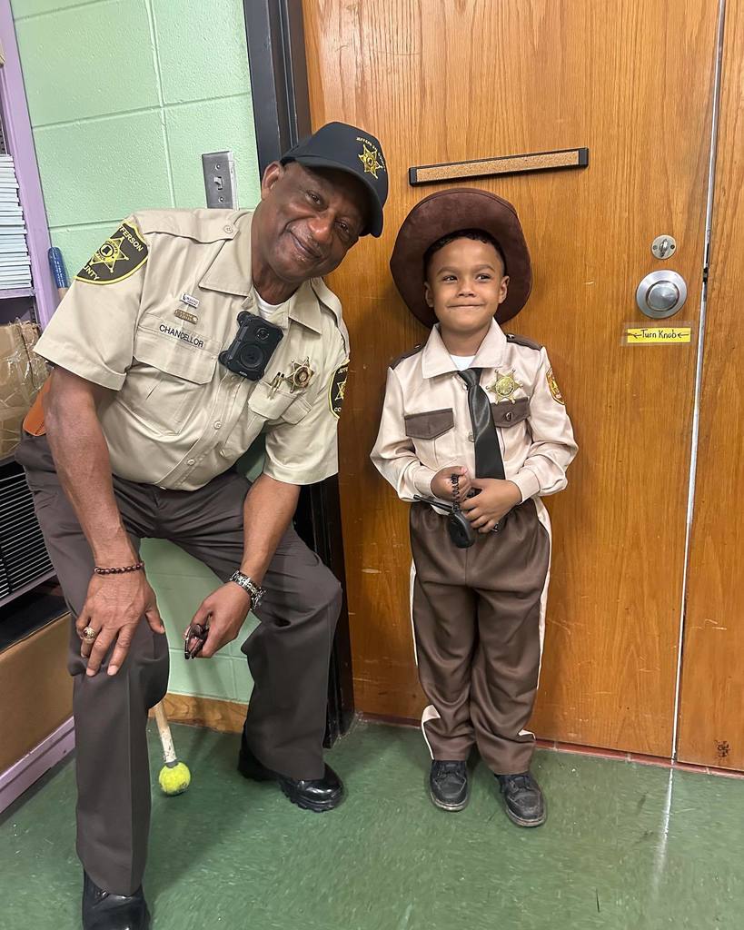 Adamsville Elementary School's School Resource Officer smiles for a photo with a student who is wearing a sheriff's deputy uniform. 