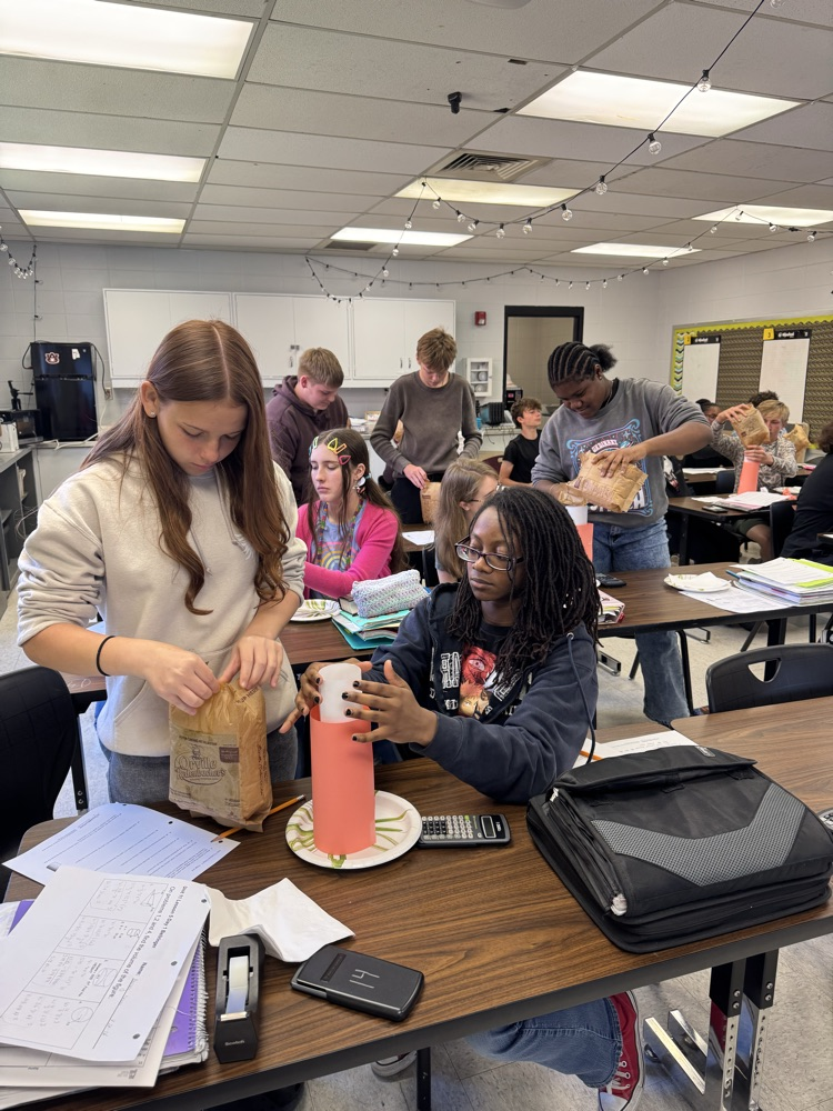 students putting popcorn into cylinders as part of a math lab.