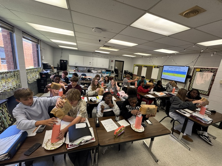 students putting popcorn into cylinders as part of a math lab.