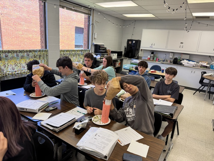 students putting popcorn into cylinders as part of a math lab.