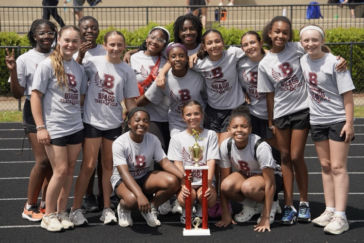Bragg Middle School’s 6th grade girls track members smile for a photo with a trophy.
