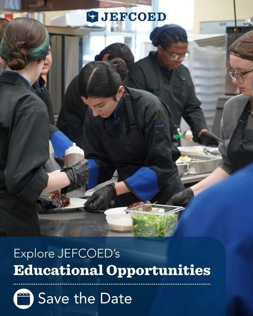 Group of high school students wearing black chef coats practicing culinary arts in a kitchen