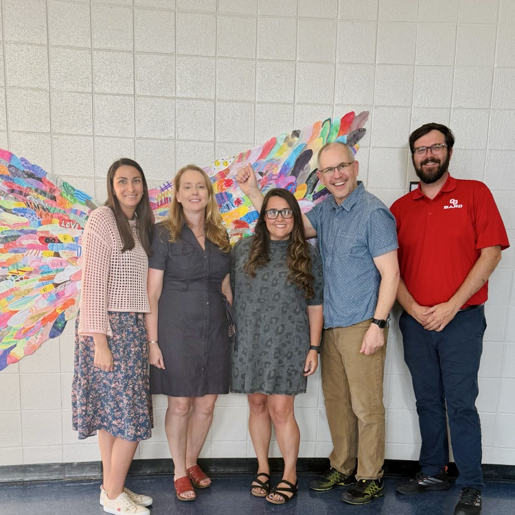 5 teachers standing together in front of artwork