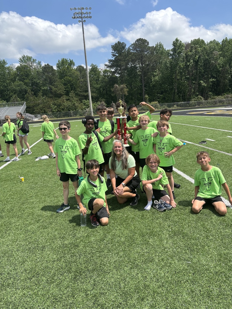 students at at a track meet posing as a group  with trophy
