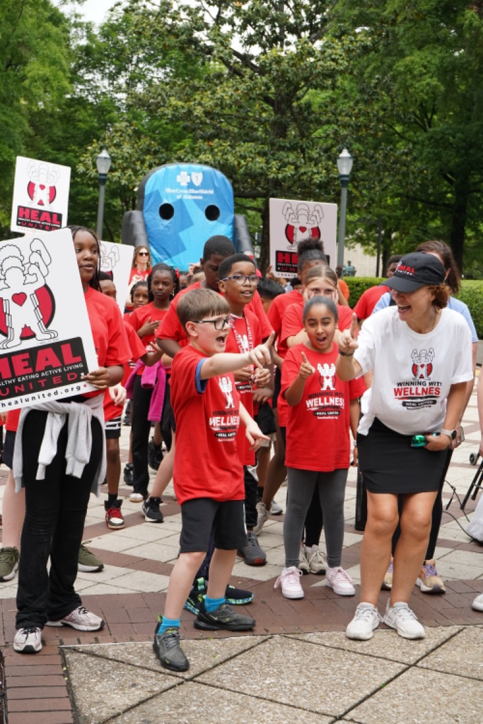 Students and adults stand at the start of a walk at Linn Park. They wear matching Healthy Eating Active Living shirts.