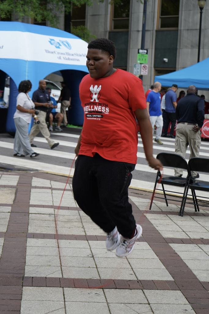 A student jumps rope at a park. He wears a “Healthy Eating Active Living” shirt.