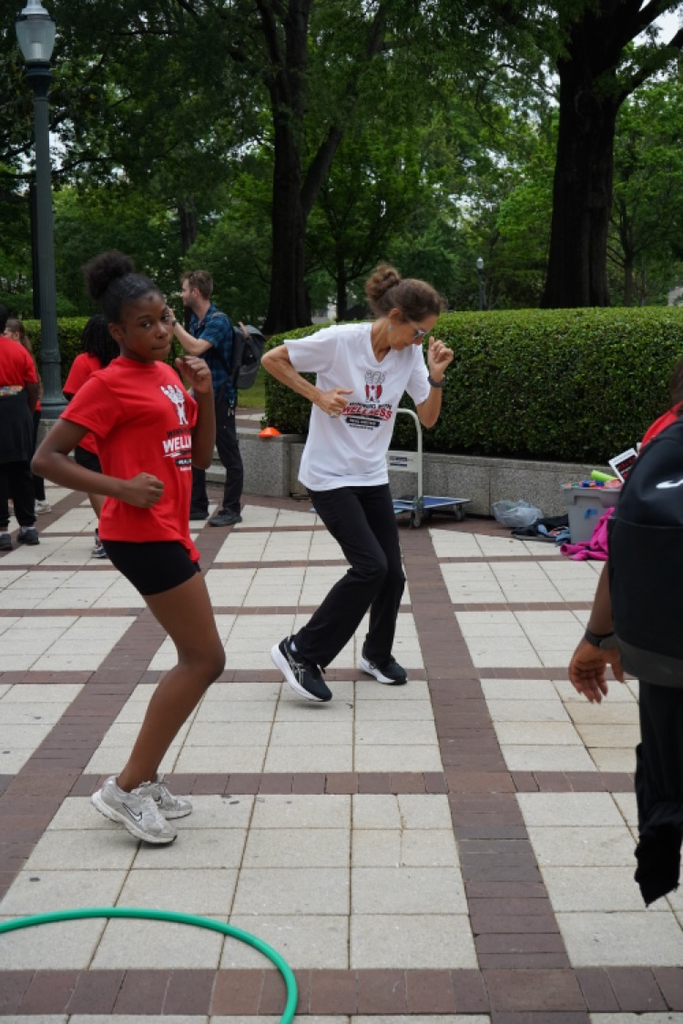 A student and an adult dance at a park.