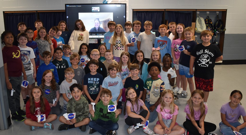 students posing in front of screen with Nasa engineer on screen