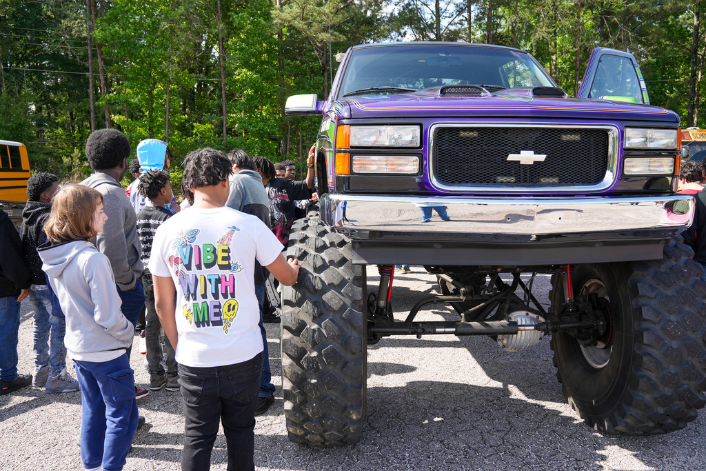 Students look at the outside of a monster truck.