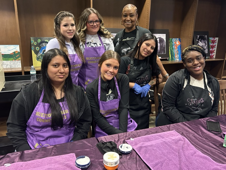 A group of Hueytown High School cosmetology students pose together for a photo inside the school library. 