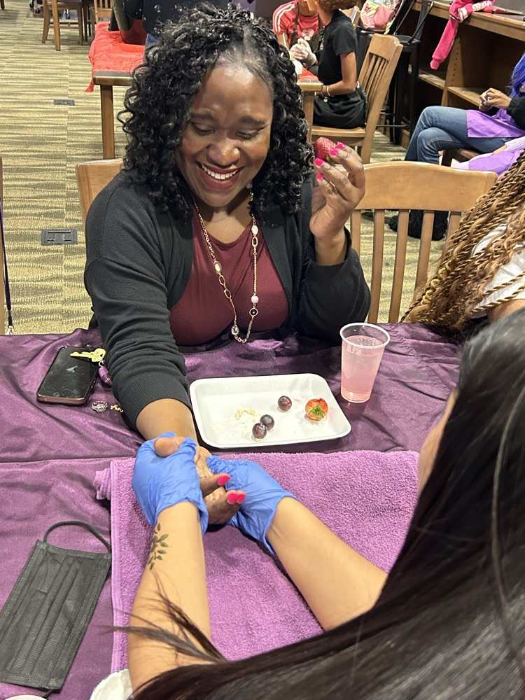 A teacher smiles while getting a hand massage inside the school library.