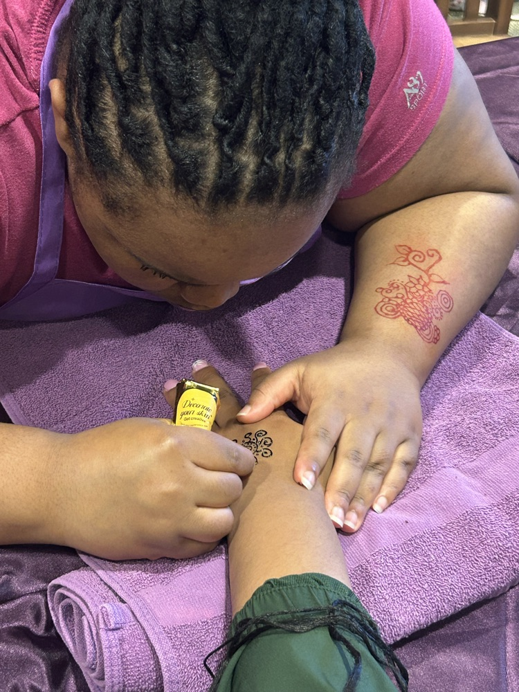 A student gives a teacher a henna tattoo.