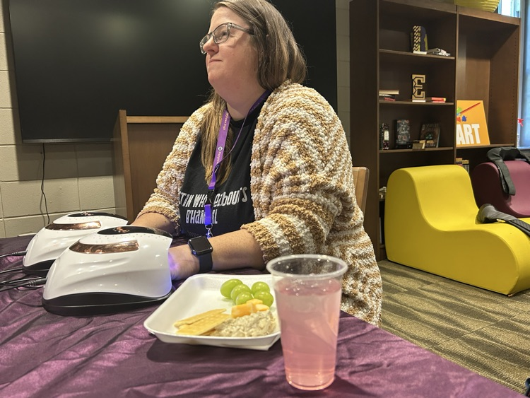 A teacher gets her nails done while sitting in a school library.