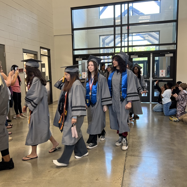 High school seniors in the caps and gowns walking the halls of McCalla Elementary 