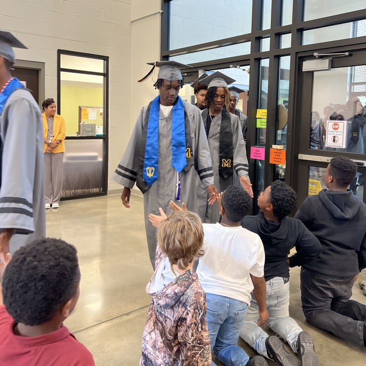 High school seniors in the caps and gowns walking the halls of McCalla Elementary