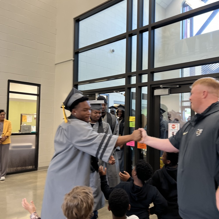High school seniors in the caps and gowns walking the halls of McCalla Elementary