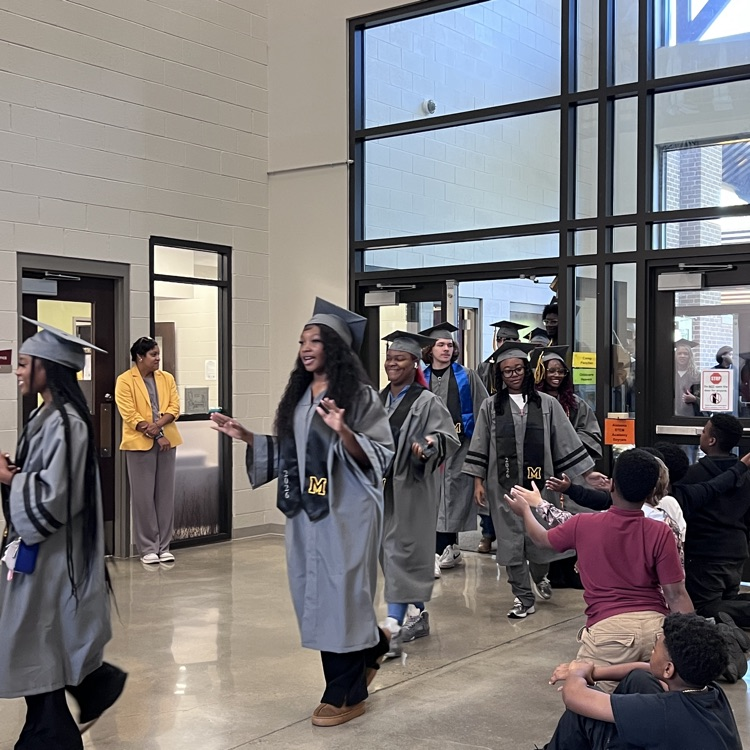 High school seniors in the caps and gowns walking the halls of McCalla Elementary