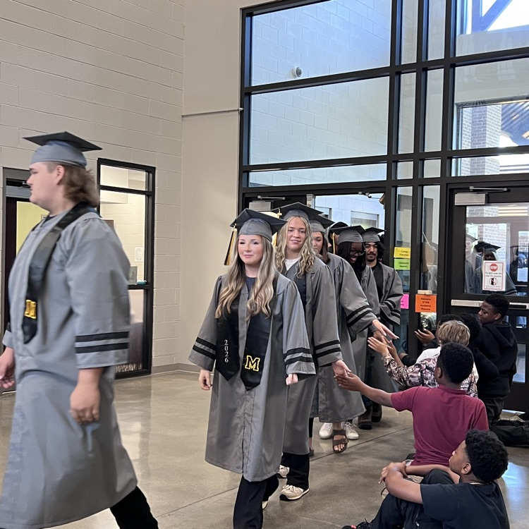 High school seniors in the caps and gowns walking the halls of McCalla Elementary