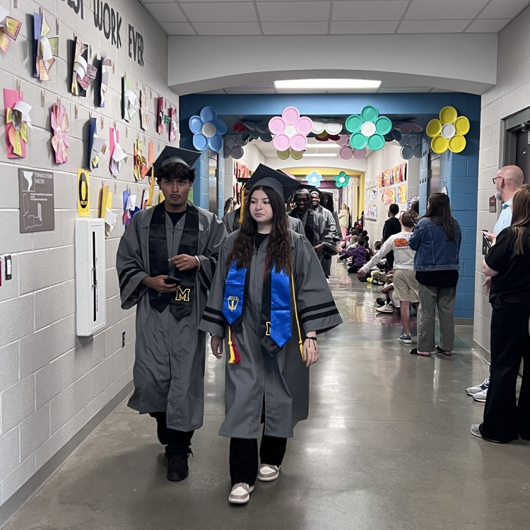 High school seniors in the caps and gowns walking the halls of McCalla Elementary