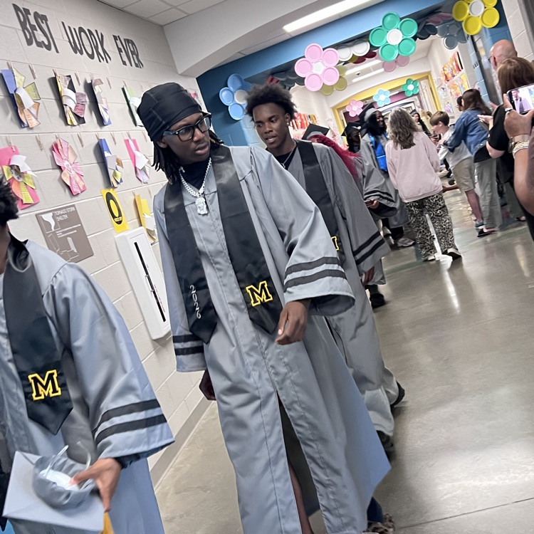 High school seniors in the caps and gowns walking the halls of McCalla Elementary